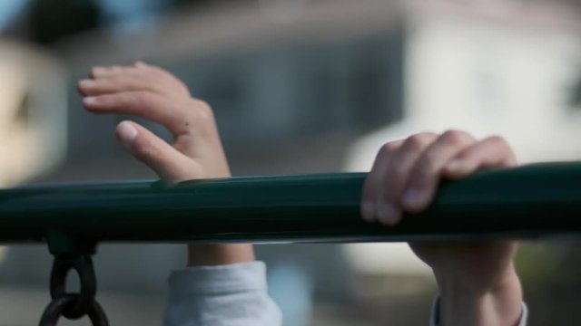 Slow motion close-up of a child moving her hands along a play structure.