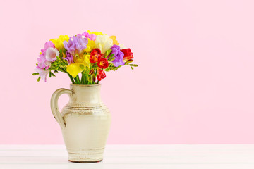 Bouquet of colorful freesia flowers in ceramic jug
