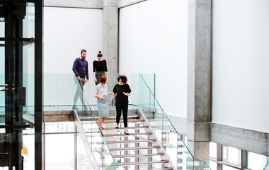 Group of young businesspeople walking down the stairs, talking.