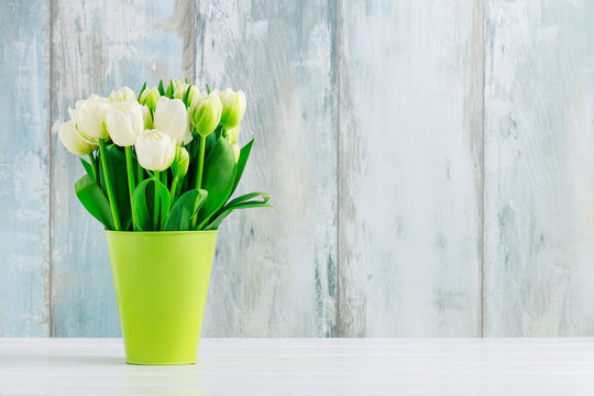 Bouquet of tulips in green bucket.