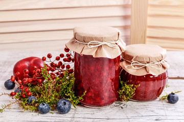 Glass jars with red jam. Autumn fruits around.