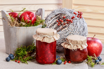 Glass jars with red jam. Autumn fruits around.