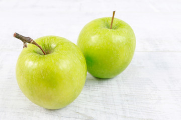 Green apples on white wooden table.