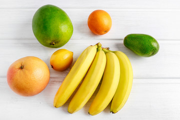 Various fruits on white wooden background.