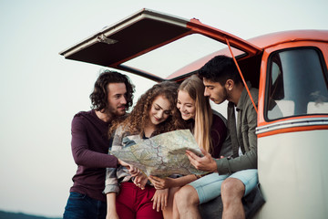 A group of young friends on a roadtrip through countryside, looking at map.