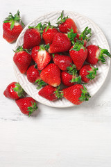 Fresh strawberries in plate on white wood