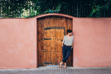 Woman waiting in front of a ancient door and pink wall