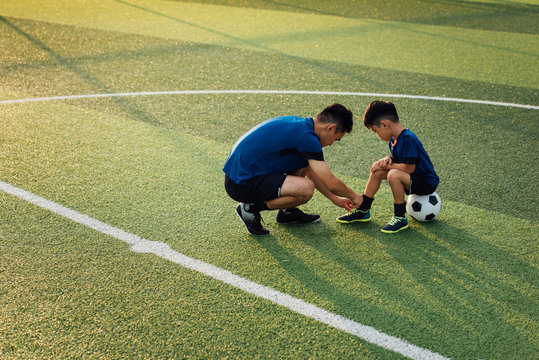 Father helping son dressing up in soccer socks