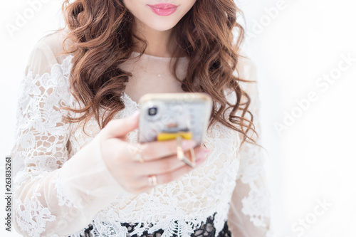 白背景スマホを持つ現代の白いレースのドレスで綺麗なお姉さん