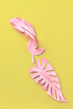 Colorful handmade leaves cut from pink paper on a yellow with pl