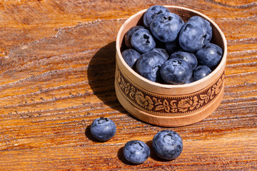 Freshly picked juicy and fresh blueberries in a Russian birch tree bark bowl on rustic vintage table. Bilberry background. Healthy eating antioxidant nutrition concept.