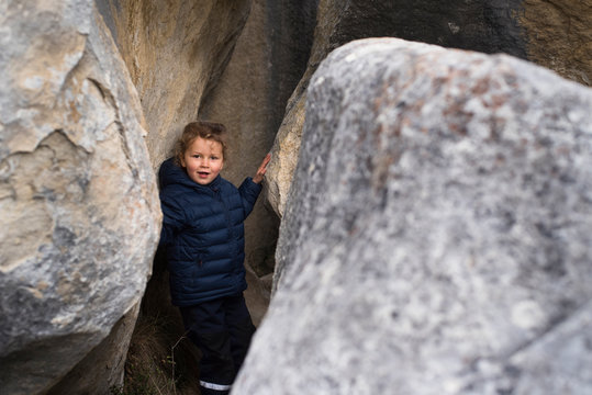Young girl exploring gaps between limestone boulders, Castle Hill, New Zealand.