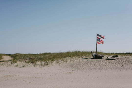 double American flags wave in wind above beach