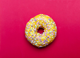 Doughnut with star shape sprinkles isolated on red color background