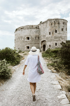Young woman with hat  walking by an old fort in Montenegro.