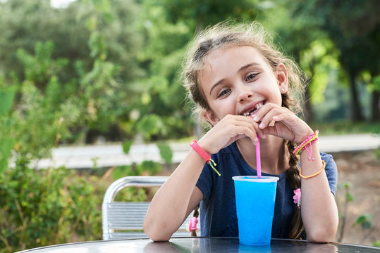 Lovely girl portrait at the park drinking slush.