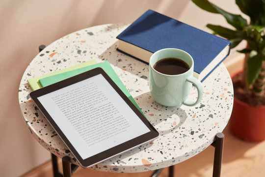 Close-up of ebook with text and cup of coffee.