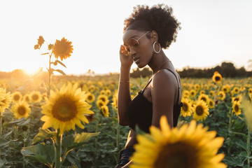 A young african american woman in a sunflower field at sunset