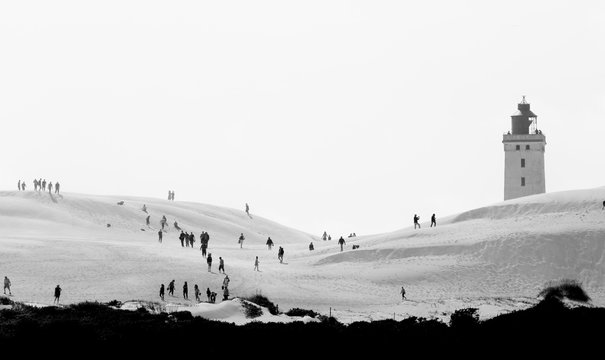 Tourists walking on a huge sand dune. A bit hazy because of the atmospheric conditions and the telelens.