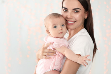 Portrait of happy mother with her baby against blurred lights. Space for text