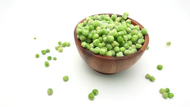 Slide shot of Frozen of fresh green peas in the wooden bowl isolated on white background