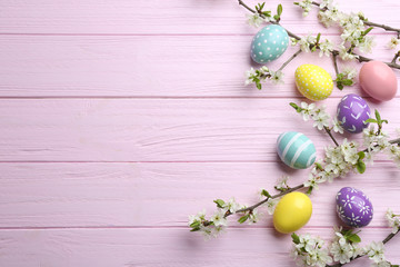 Fototapeta na wymiar Flat lay composition with painted Easter eggs and blossoming branches on wooden background. Space for text
