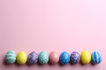 Fototapeta na wymiar Flat lay composition of painted Easter eggs on color background, space for text