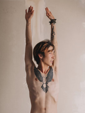 Shirtless Asian man smiling and holding hands up