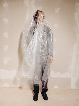Young man covered with plastic bag standing in room