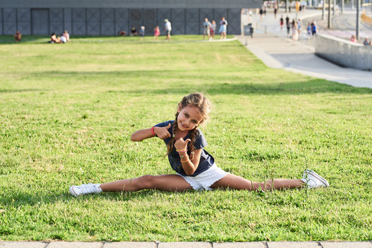 Happy kid doing split at park.