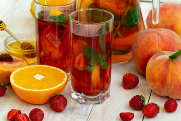 healthy drink concept. strawberry, peach mojito cocktail with lime,orange. mint and honey, cold refreshing drink or beverage. Glasses of berry, fruit compote with pieces of orange and strawberry.