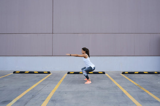 Sportswoman warm up exercises with body. Squats.