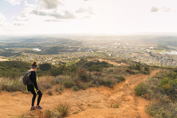Woman hiking a trail along along a ridge.