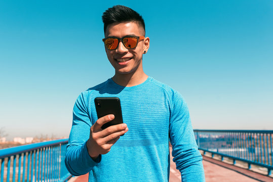 Handsome asian runner man using mobile