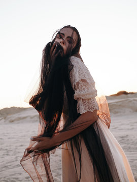 Young woman in white dress touching veil