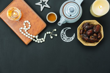Table top view aerial image of decorations Ramadan Kareem holiday background.Flat lay date with rosary & lighting and cup of tea.Halal meal set for fasting is obligatory for Muslim on black wooden.