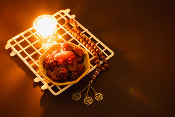 Fototapeta na wymiar Table top view aerial image of decorations Ramadan Kareem holiday background.Flat lay dates with brown rosary & lighting.Halal meal set for fasting is obligatory for Muslim on black wooden.low key