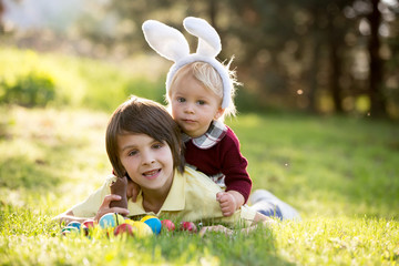 Sweet children, boy brothers with bunny ears, egg hunting for Easter, child and Easter day traditions