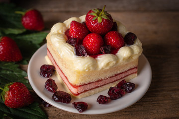 strawberry layer cake topping strawberry putting on the white plate on the wood table background.