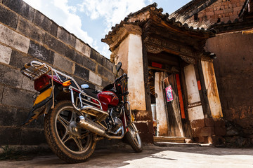 Old school motorbike in front of traditional Chinese house
