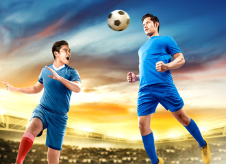 Two asian football player man jump in the air and duel heading the ball