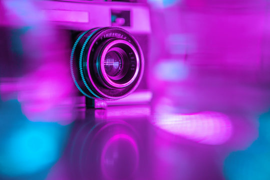 Old retro camera under colorful neon lights