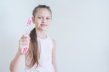 Cheerful cute girl brushes her teeth with a pink brush