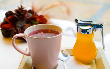 berries tea mug with honey and a teaspoon on a tray and decoration