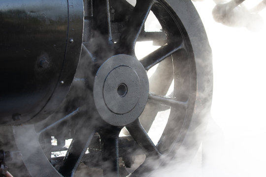 Wheel of a heritage steam train with steam
