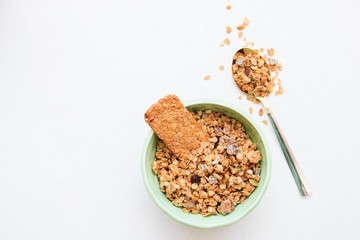 Crispy muesli in boal and on spoon dry Breakfast isolated on white background selective focus, top view