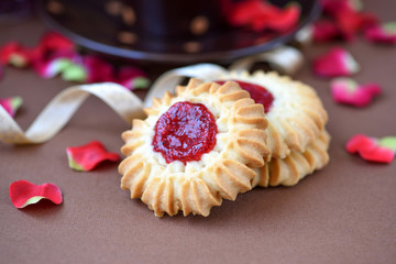 Shortbread cookies with jam in the middle on plate against brown background