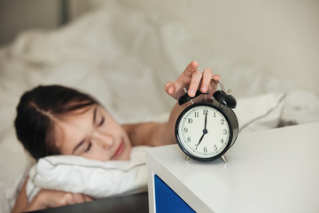 Child wakes up in the morning with alarm clock on bed