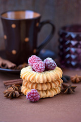 Shortbread cookies with frozen raspberries on brown background