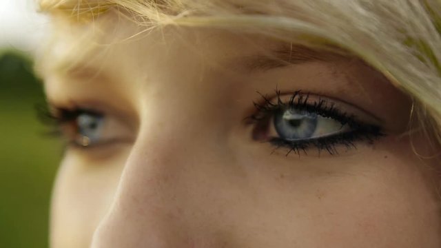 Detail shot of a girl with blue eyes gazing into the distance in slowmotion
